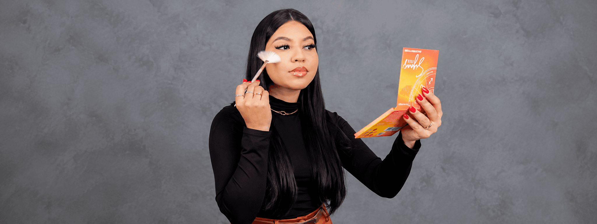 Karol Carvalho aplicando maquiagem em si mesma, com a paleta na mão